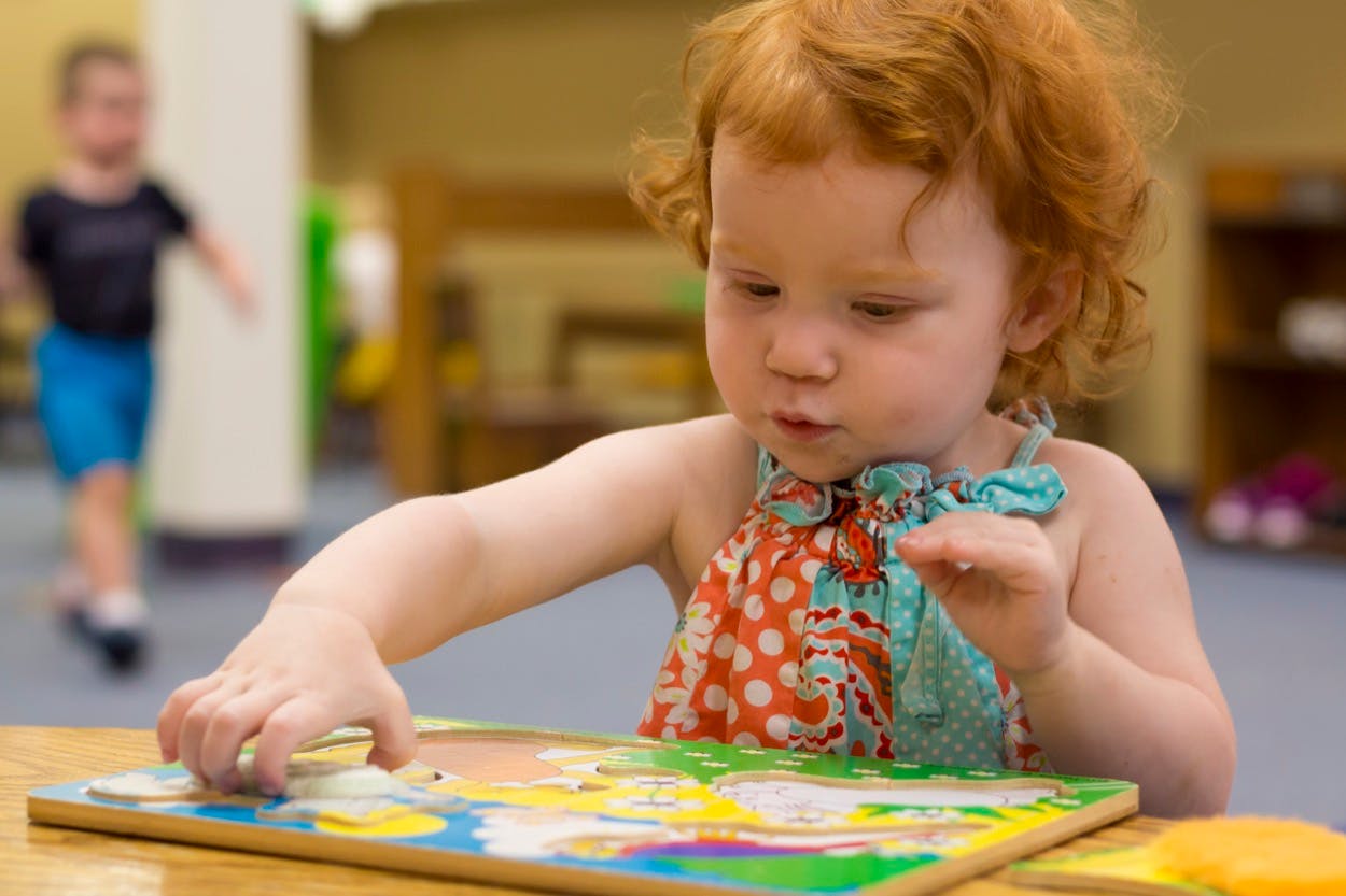 Child with red hair playing with a puzzle