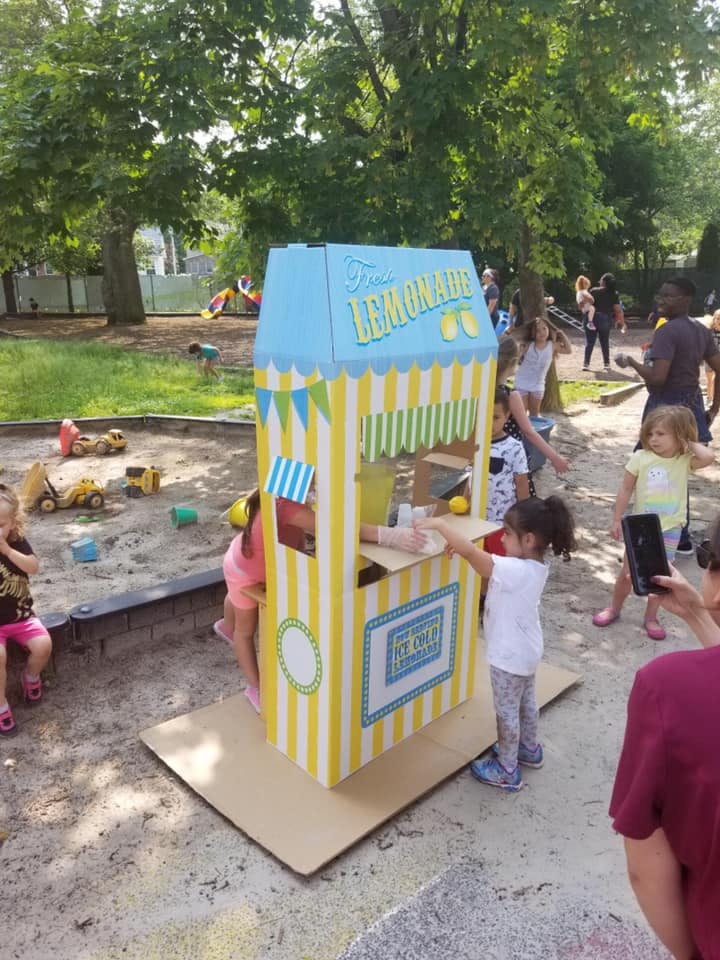 Children playing with a toy lemonade stand outdoors