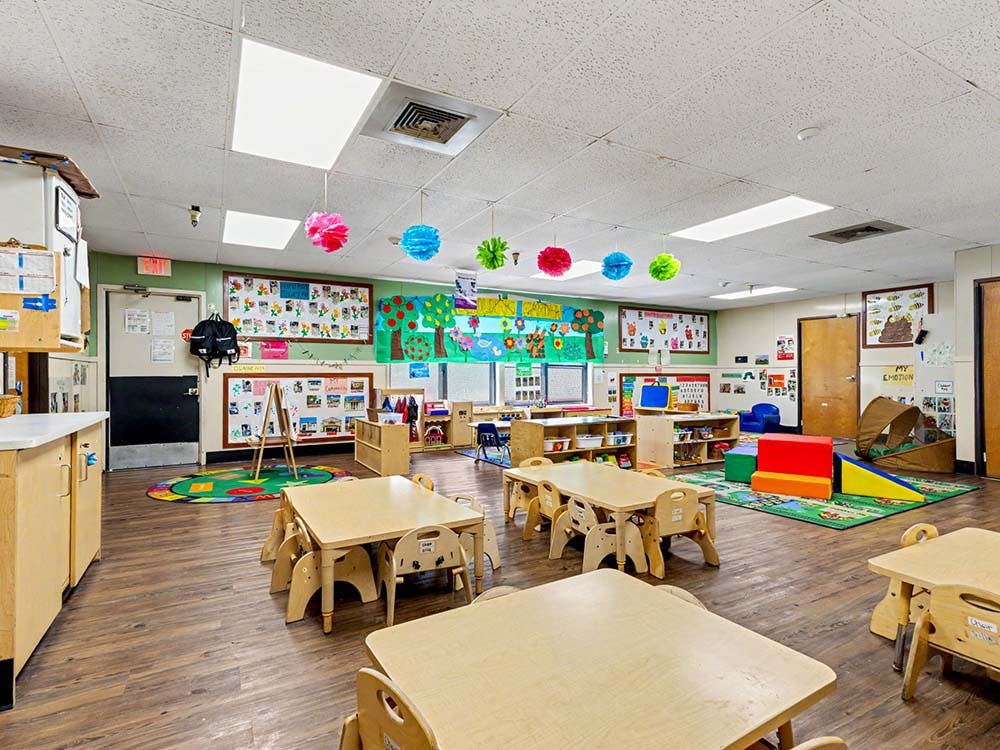 Empty classroom with small tables, chairs, and colorful decorations