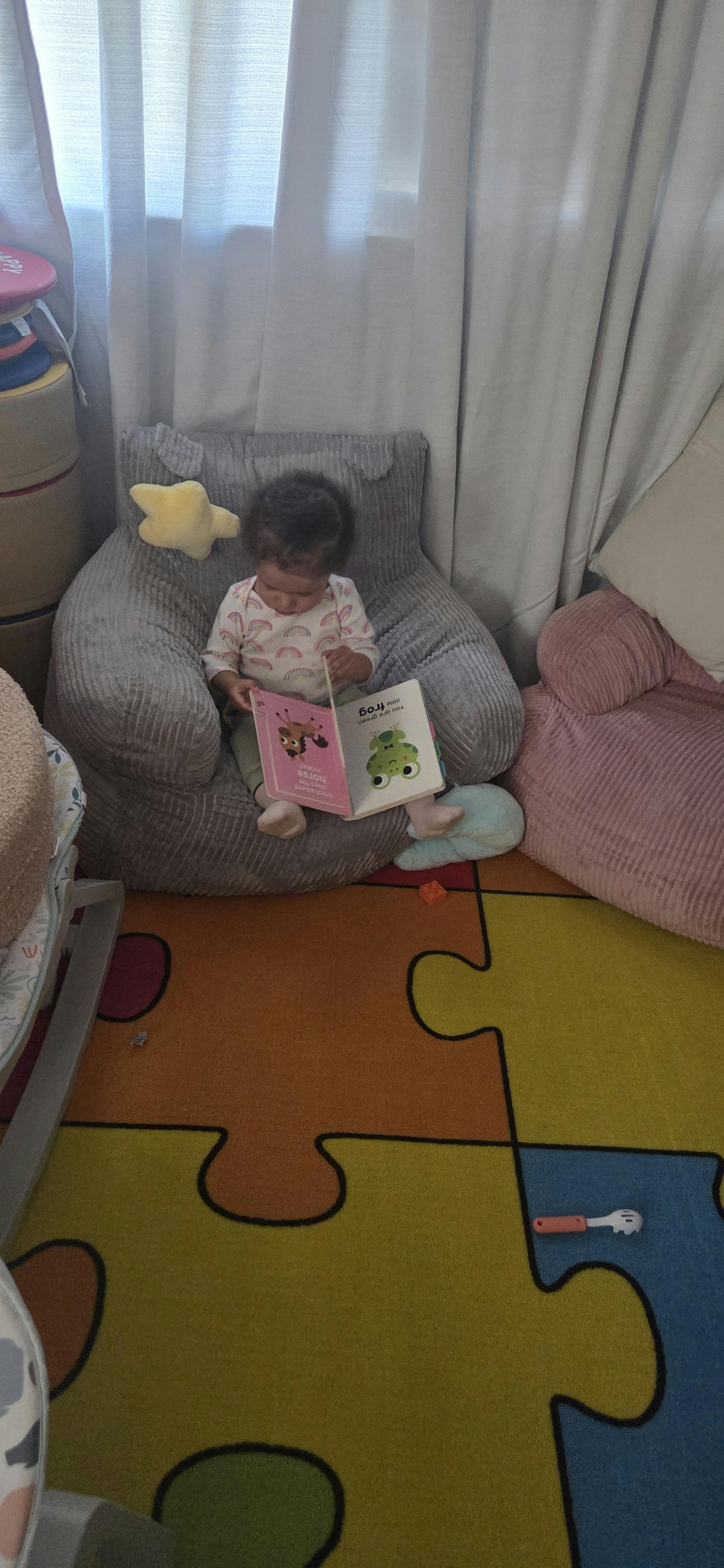 Child sitting in a soft chair reading a book