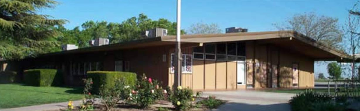 Single-story building with a flagpole in front