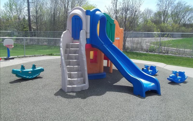 Colorful playground structure with a slide and stairs, along with several spring riders