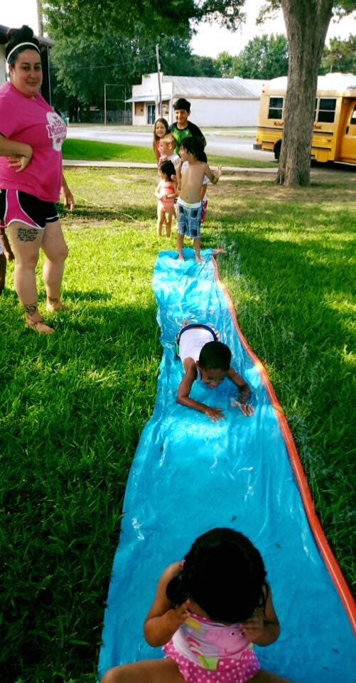 Person and children playing on a blue slip and slide