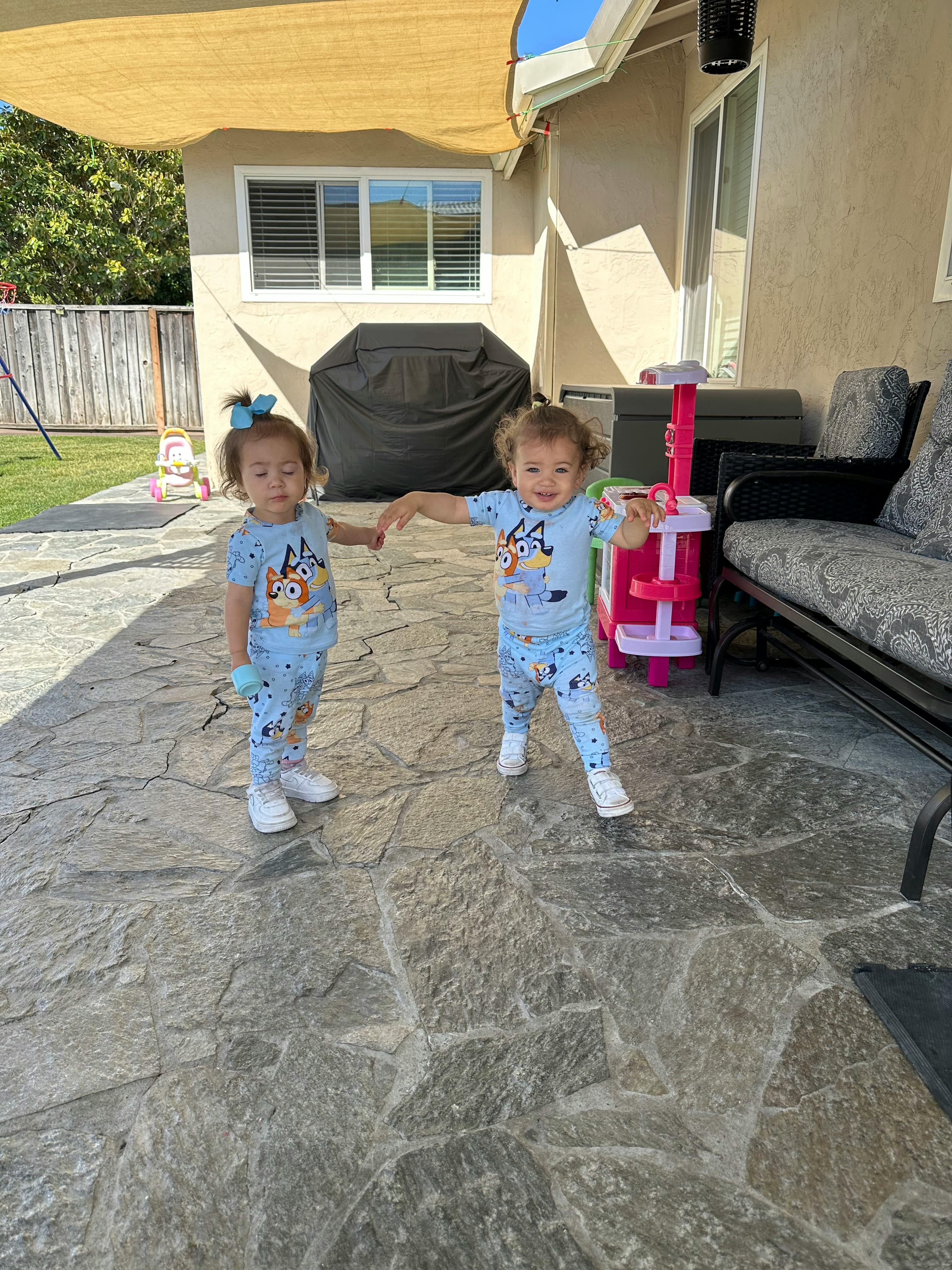 Two children holding hands on a patio