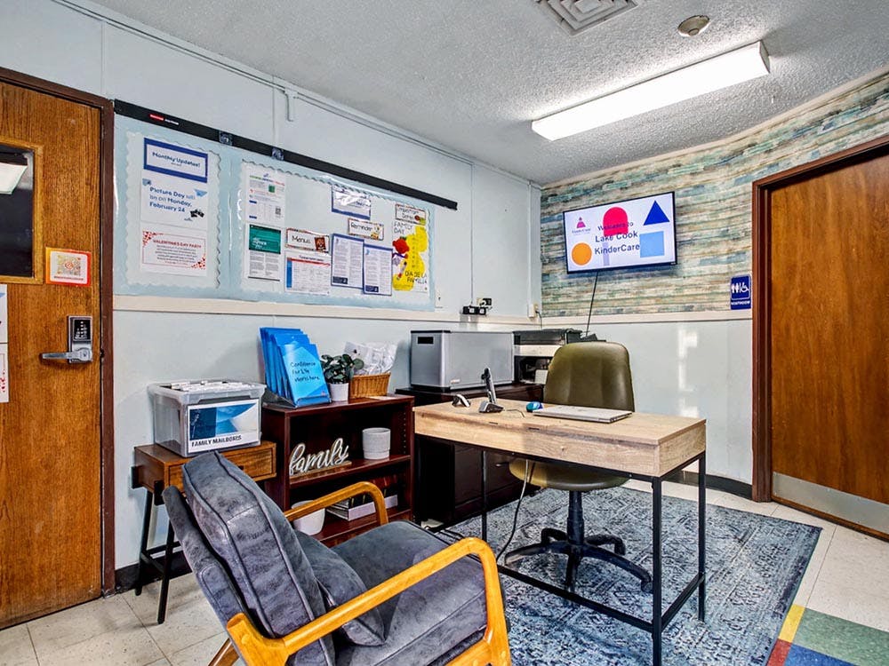 Reception area with a desk, office chair, and bulletin board with notices