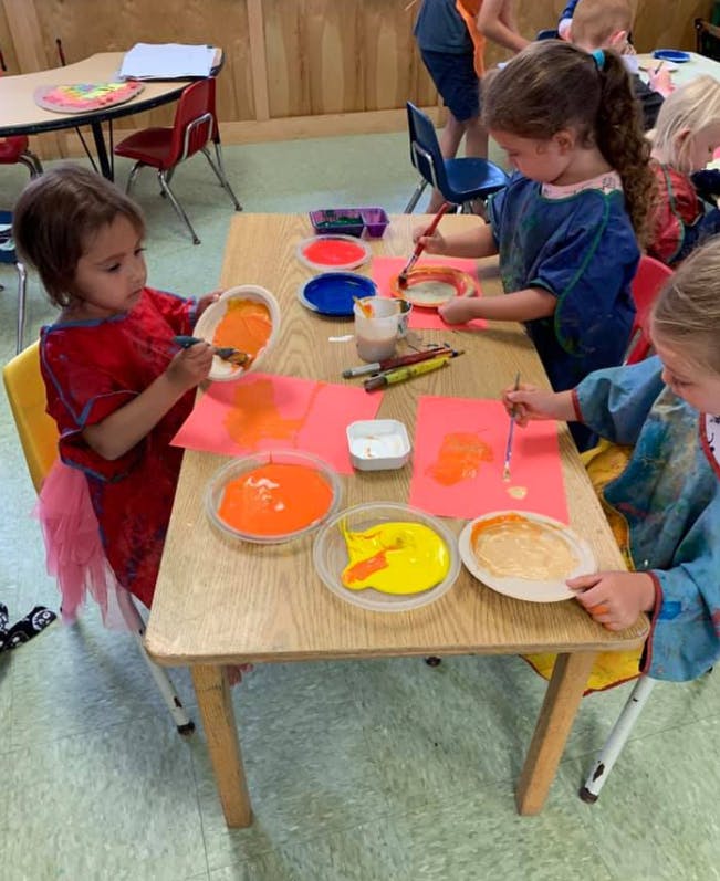 Children painting at a table in a classroom