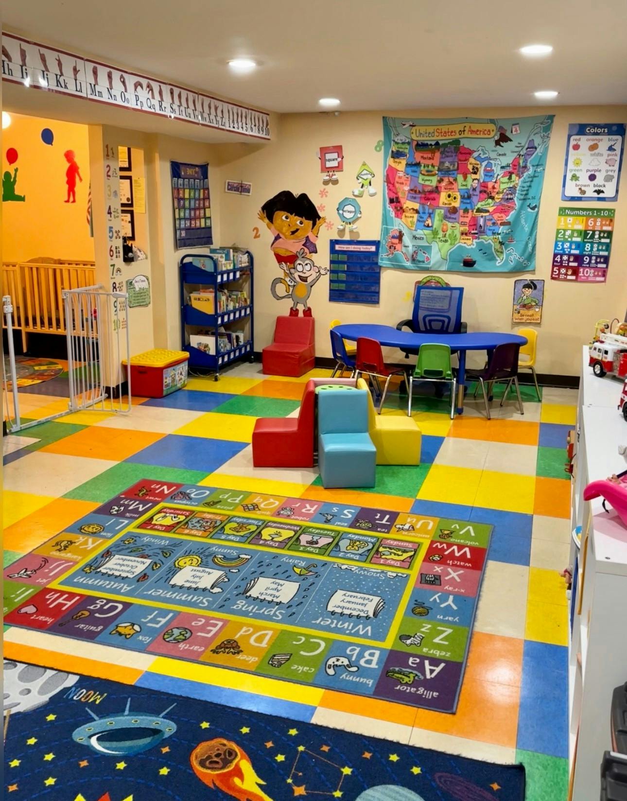 Colorful classroom with play mats, small tables, and wall decorations