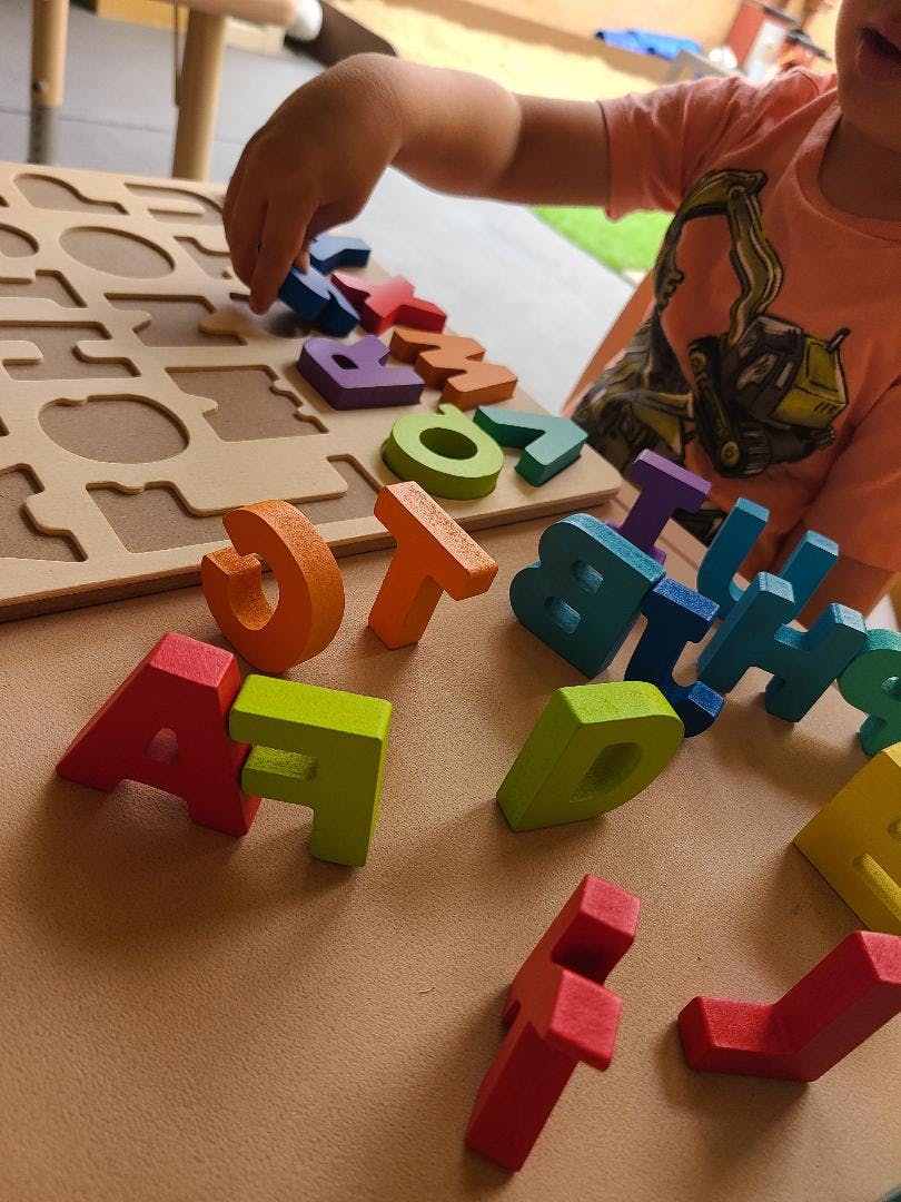 Child playing with colorful wooden alphabet letters and a puzzle board