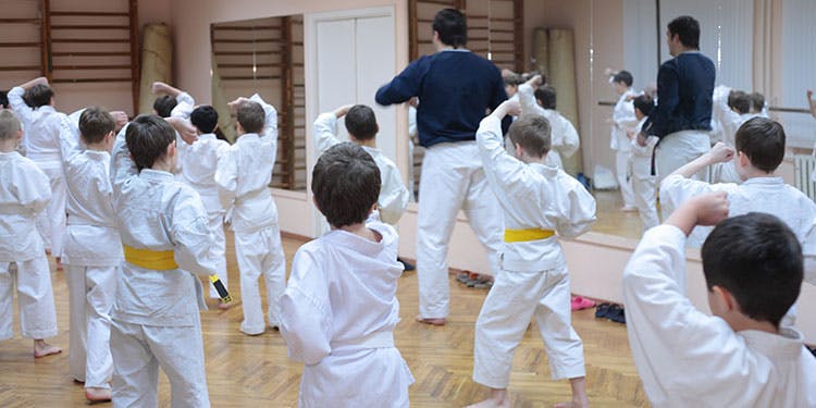 Adult and children in white uniforms practicing martial arts