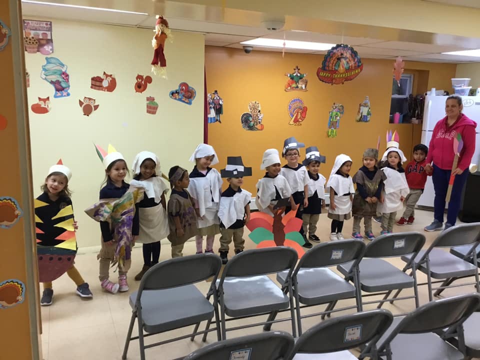 Group of children in costumes standing in a line with an adult