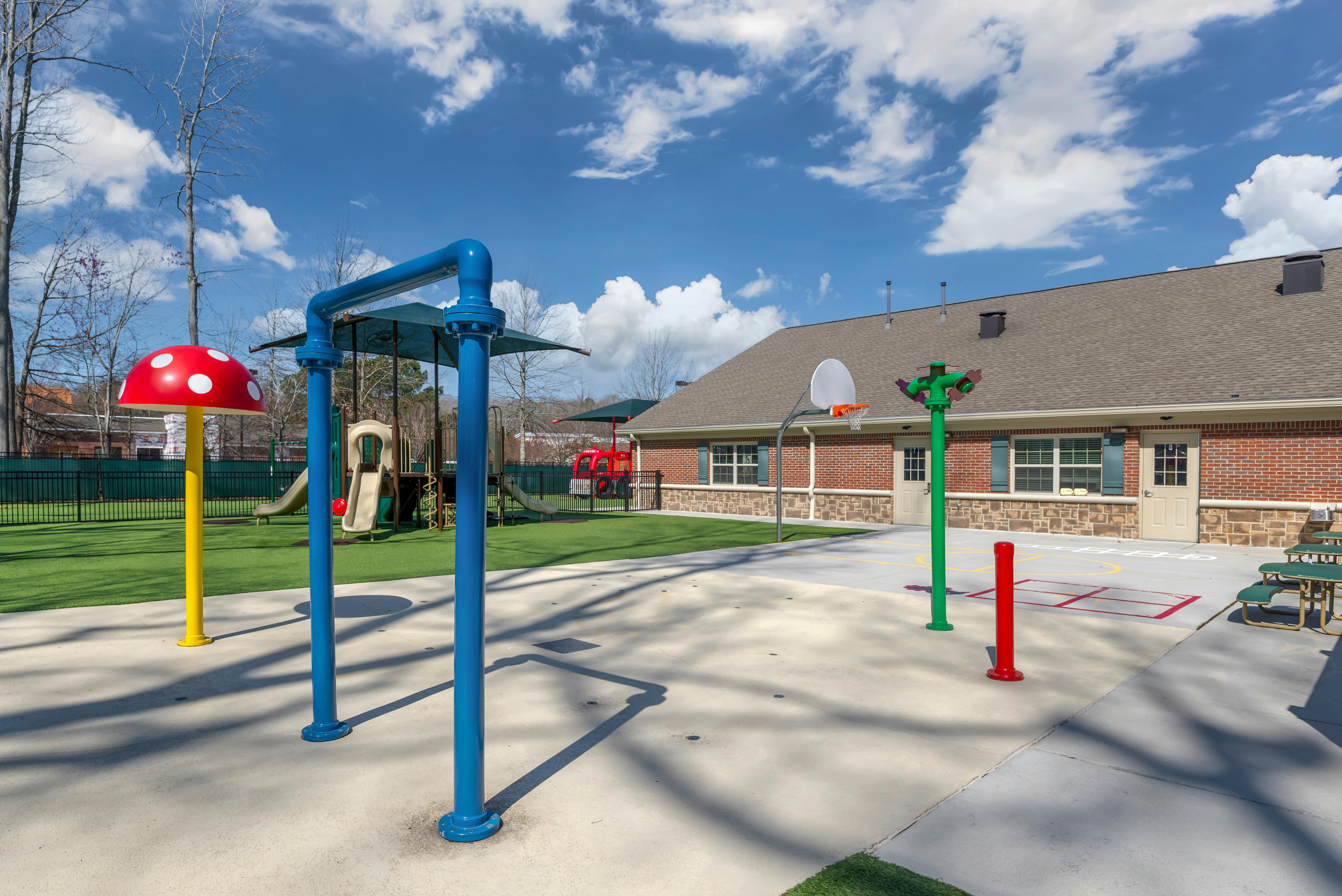 Playground with artificial turf and a red brick building in the background
