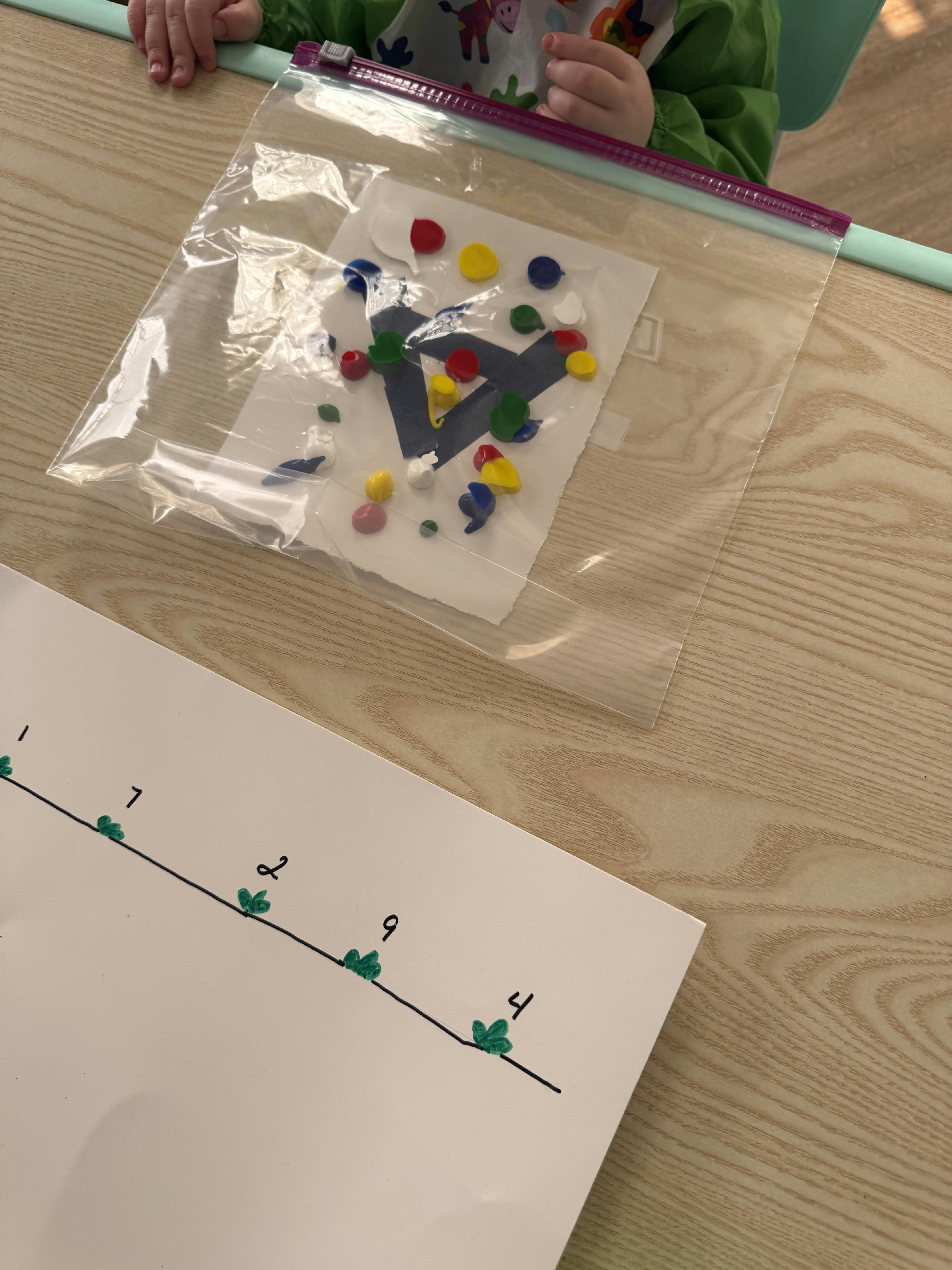 Child engaging in a sensory craft project with paint in a sealed plastic bag