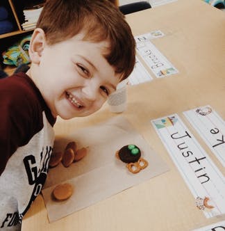 Child smiling at a table with snacks and snacks