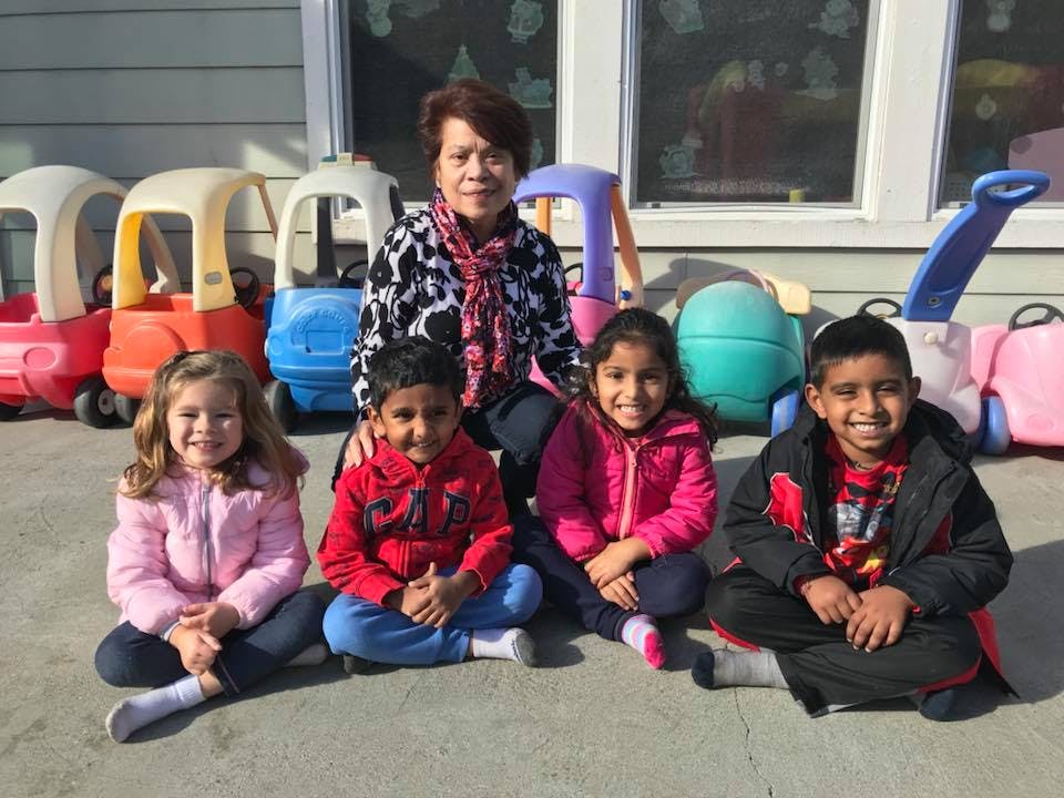 Adult and four children sitting on the ground outdoors