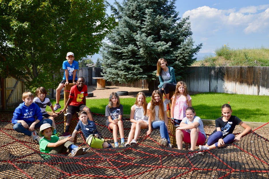 Group of children and teens sitting and standing on a large net