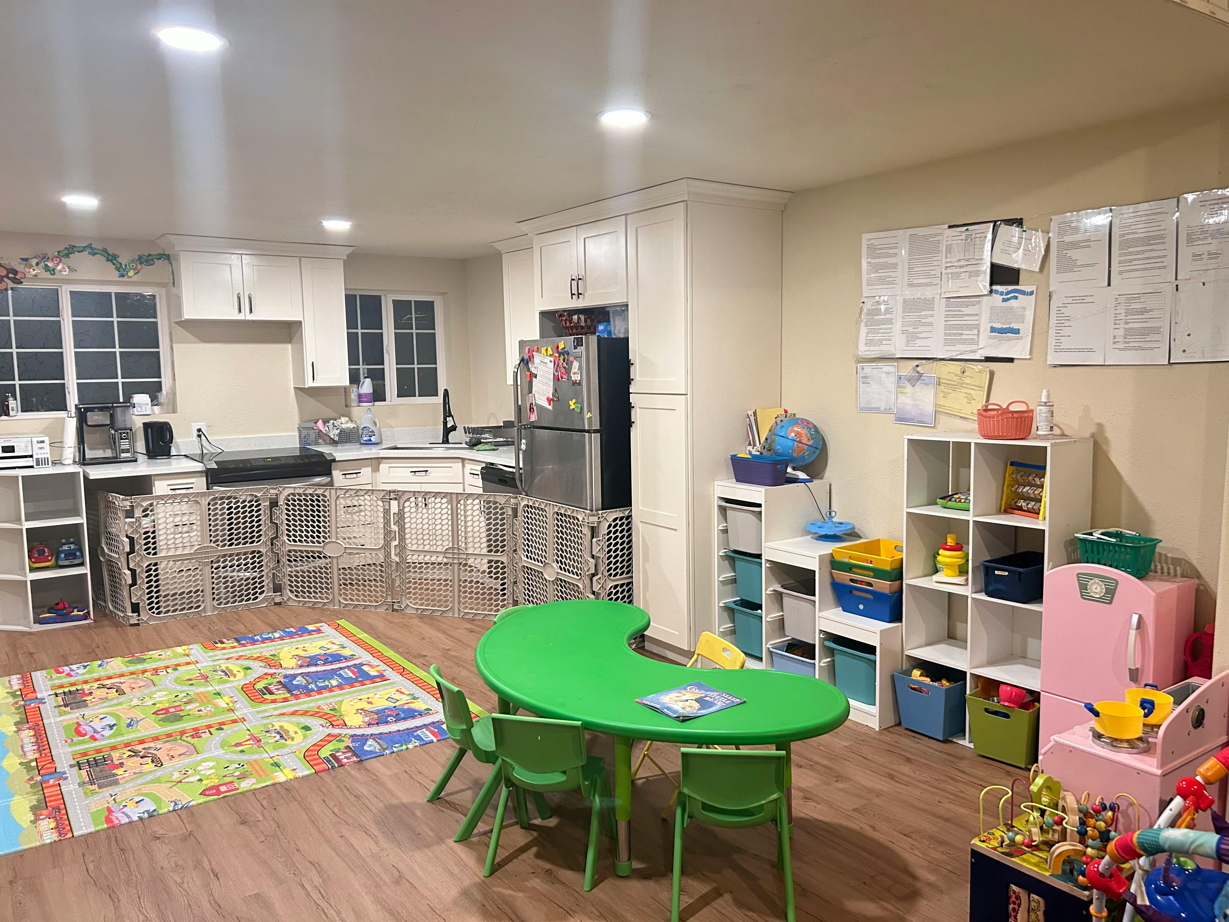 Kitchen area with a child safety gate and a green play table with chairs