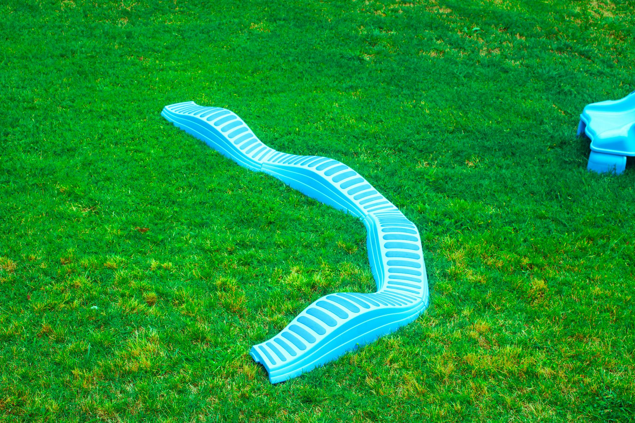 A blue plastic balance beam on green grass