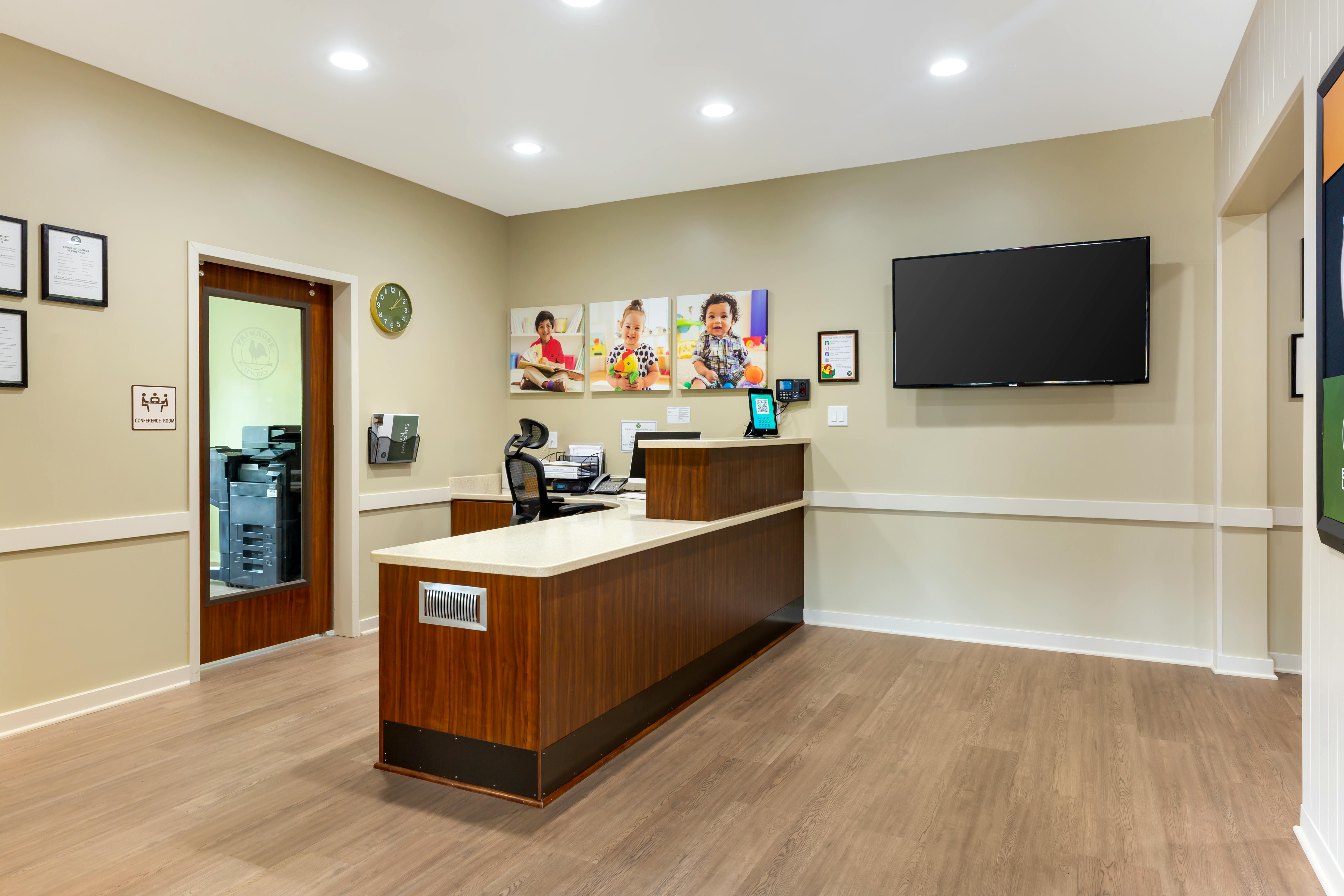 Reception area with a wooden desk, screen, and child artwork
