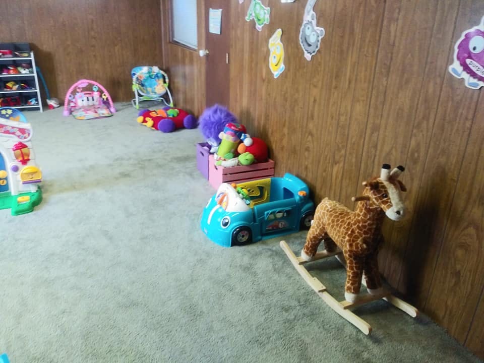 Playroom with various toys including a rocking giraffe and blue car