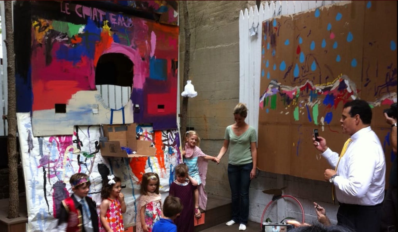 Adults and children standing near large colorful paintings
