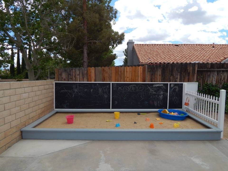 Sandbox with toys and a small white fence