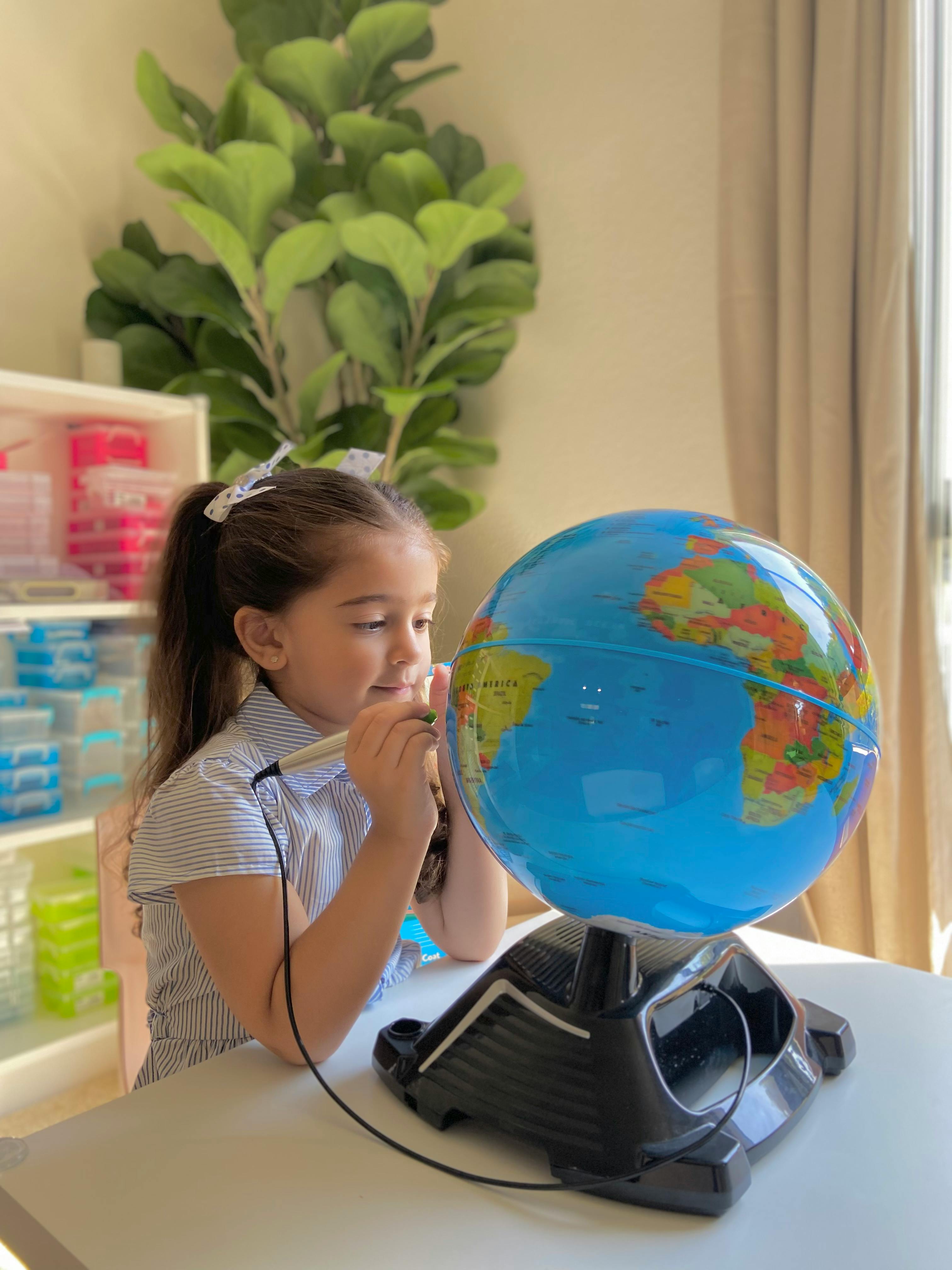 Child looking at a globe with a pointing stick