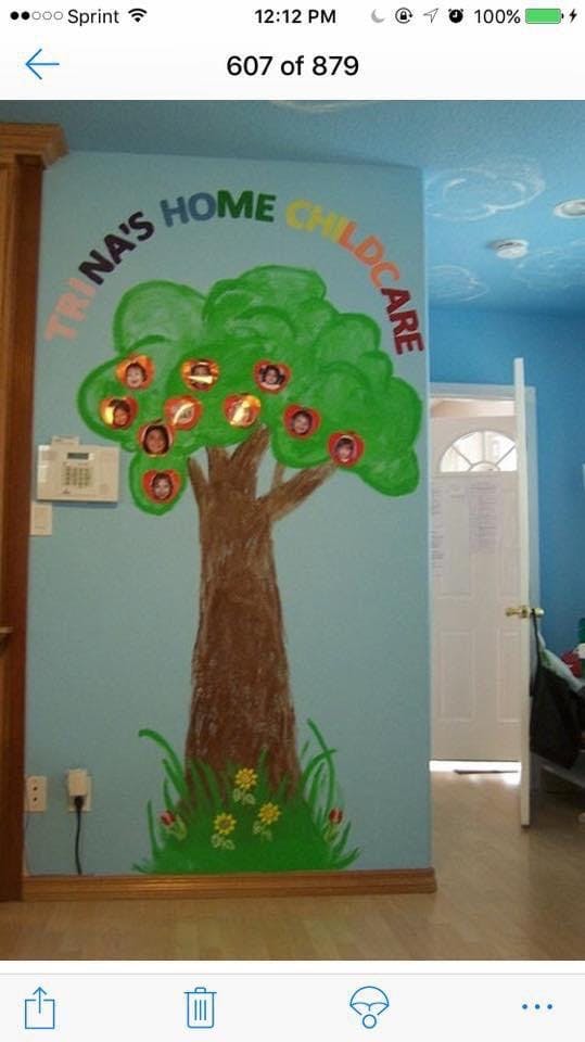 Wall mural of a tree with photos of children in its leaves, text "TRINA'S HOME CHILDCARE"