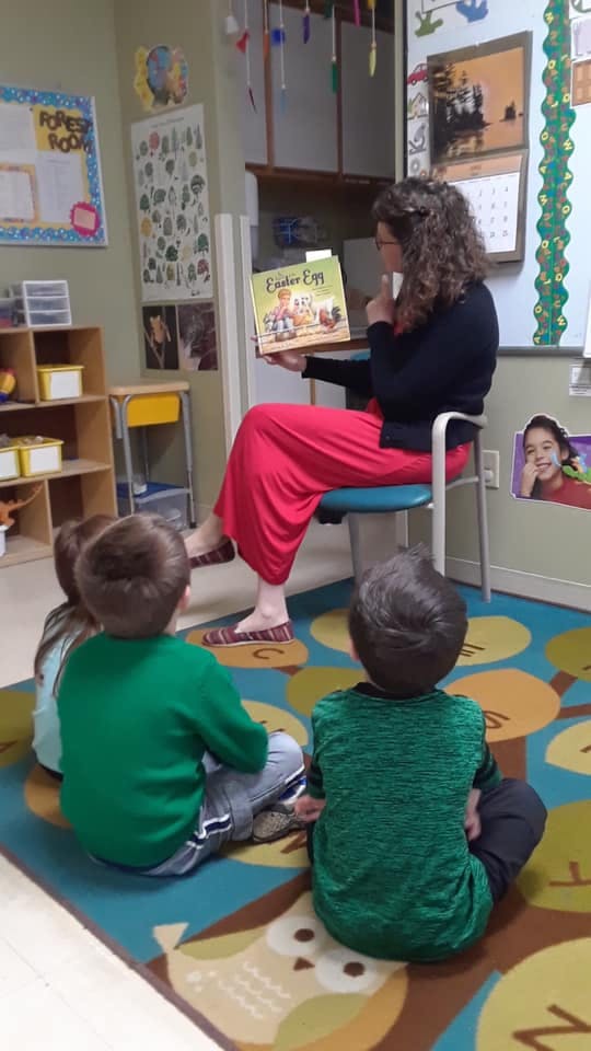 Person reading a book to children in a classroom