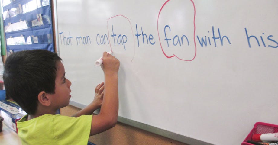 Child writing on a whiteboard in a classroom