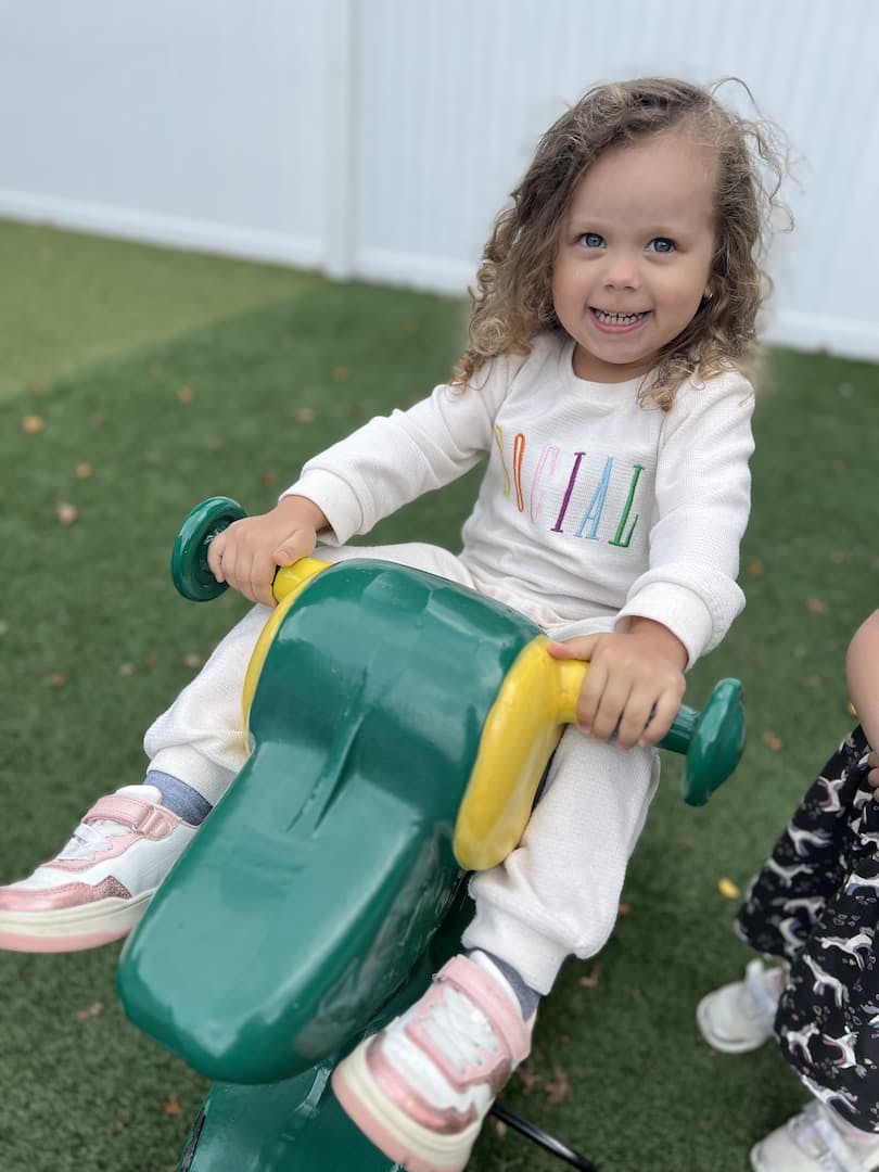 Child on a green and yellow ride-on toy