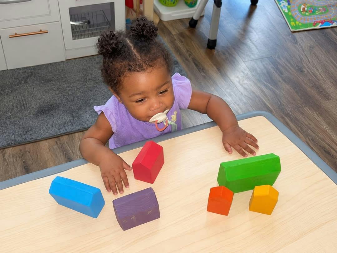 Child playing with wooden house-shaped blocks on a table