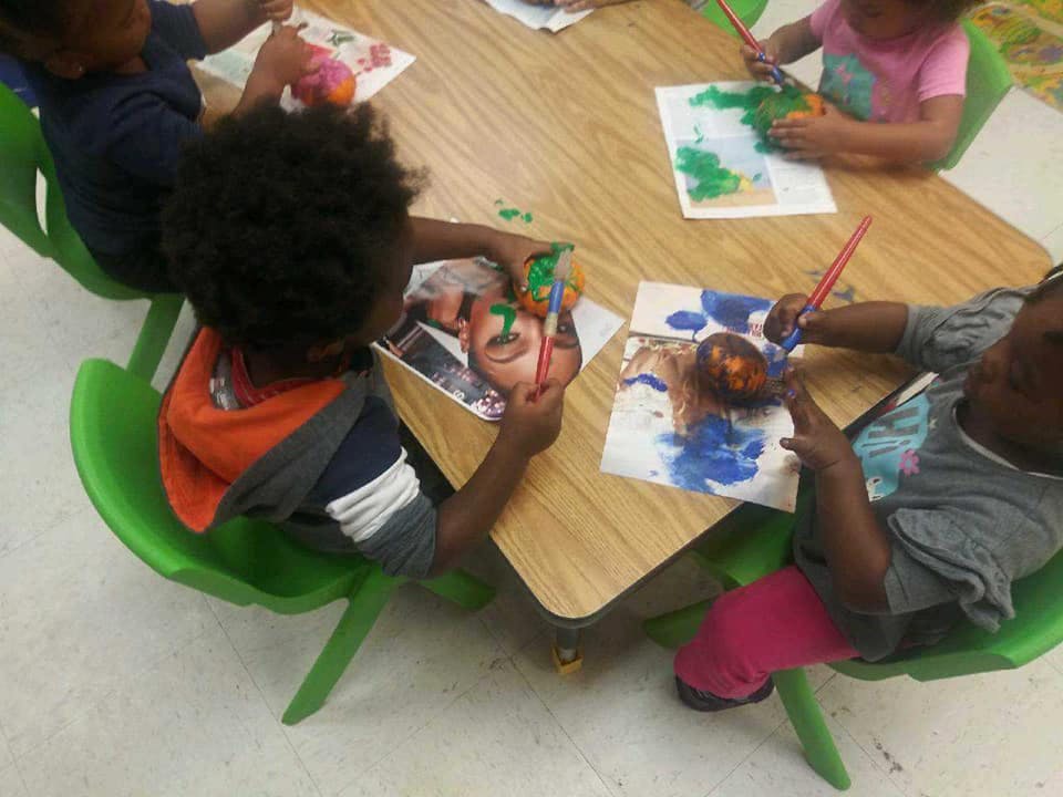 Children painting at a table in a classroom