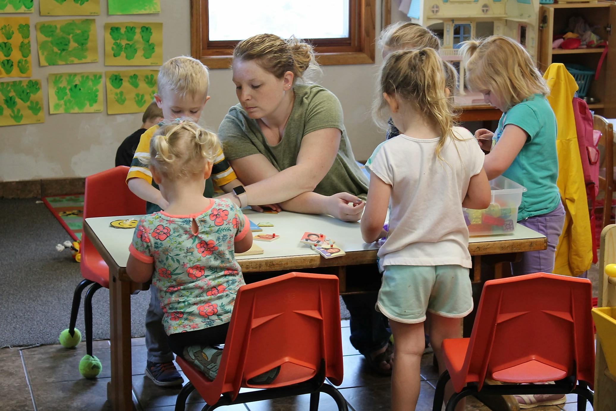 Adult and children gathered around a table in a classroom