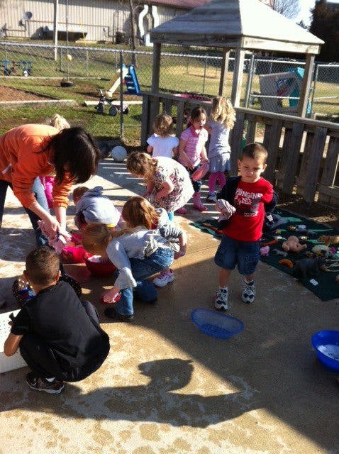 Adult and children gathered around bowls on a playground