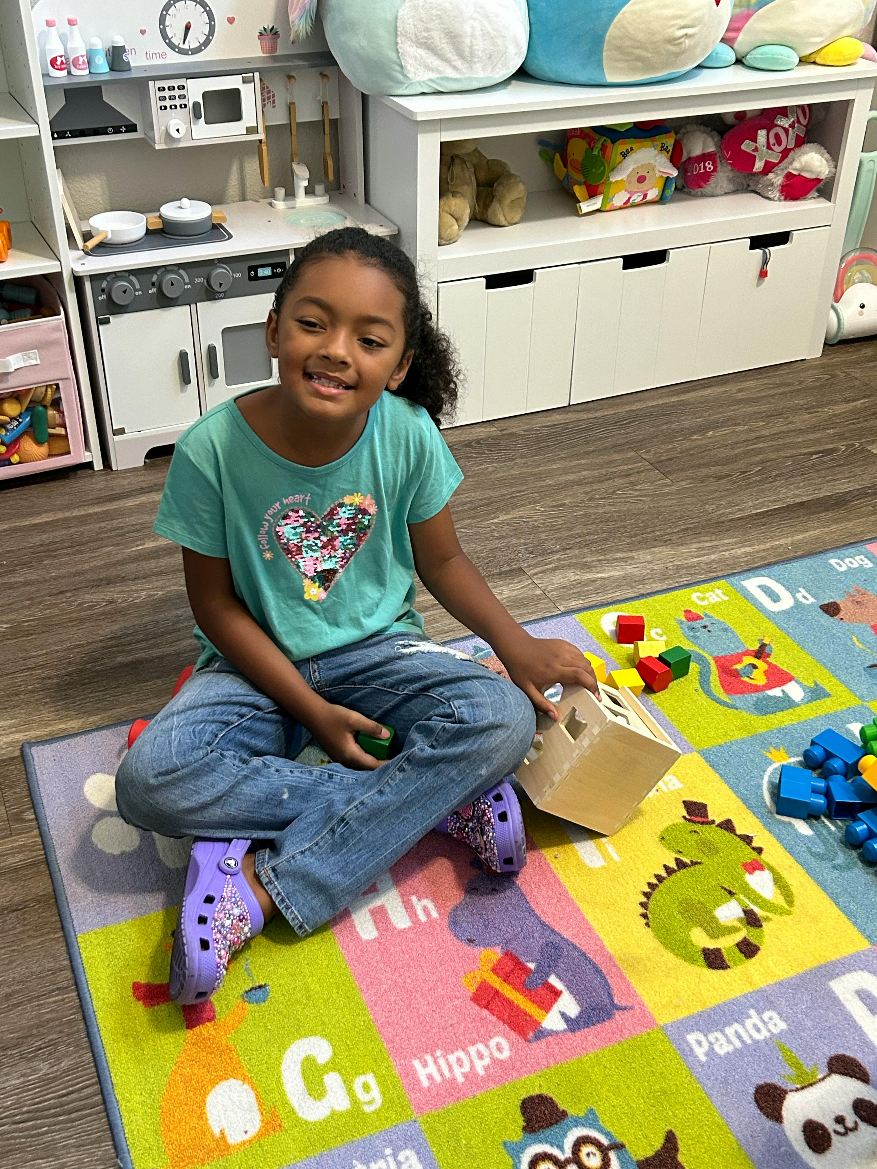 Child sitting on a rug with toys