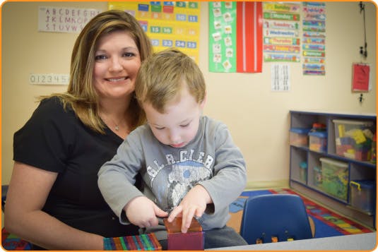Adult and child playing with blocks in a classroom