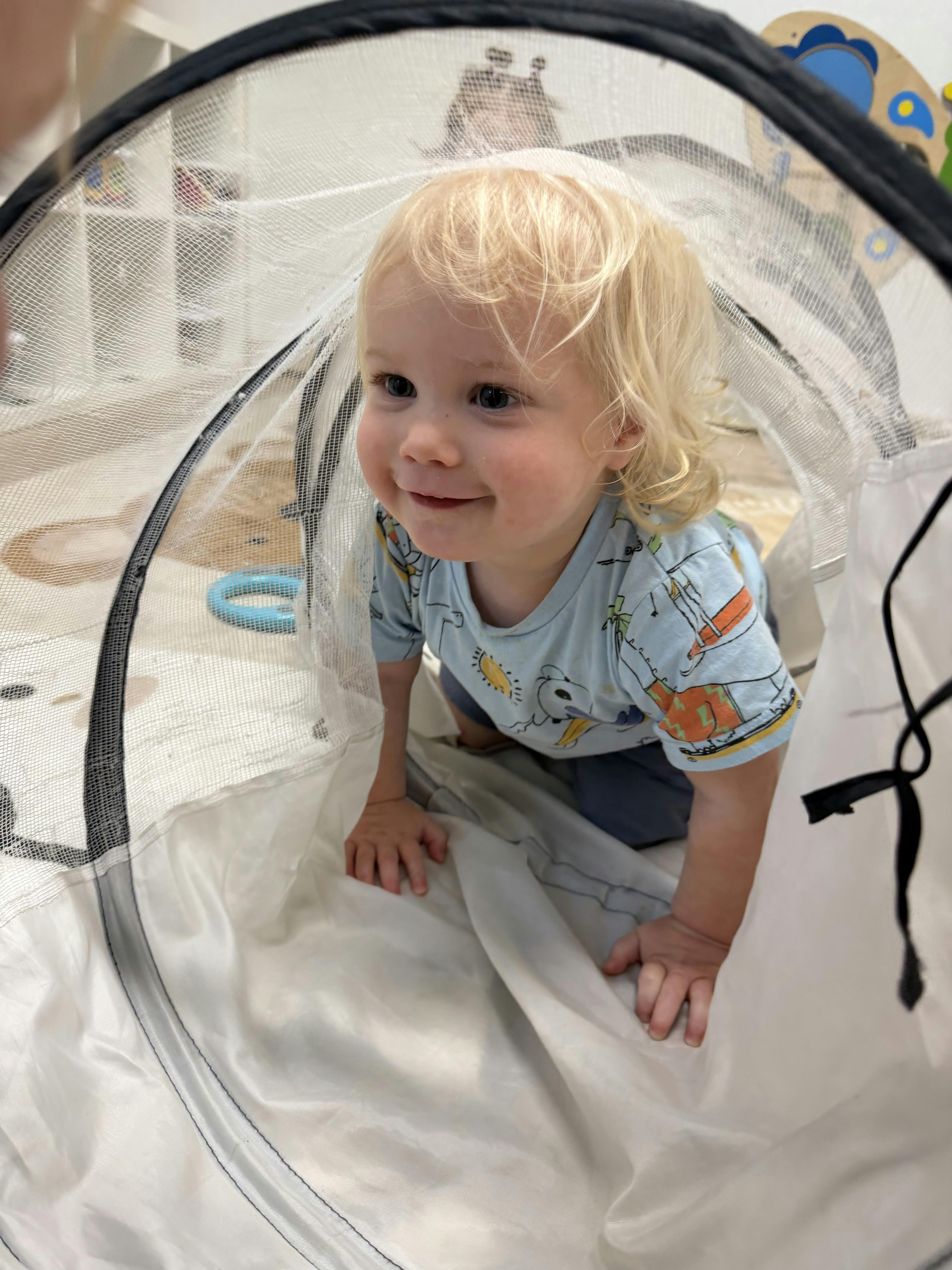 Child crawling inside a mesh play tunnel