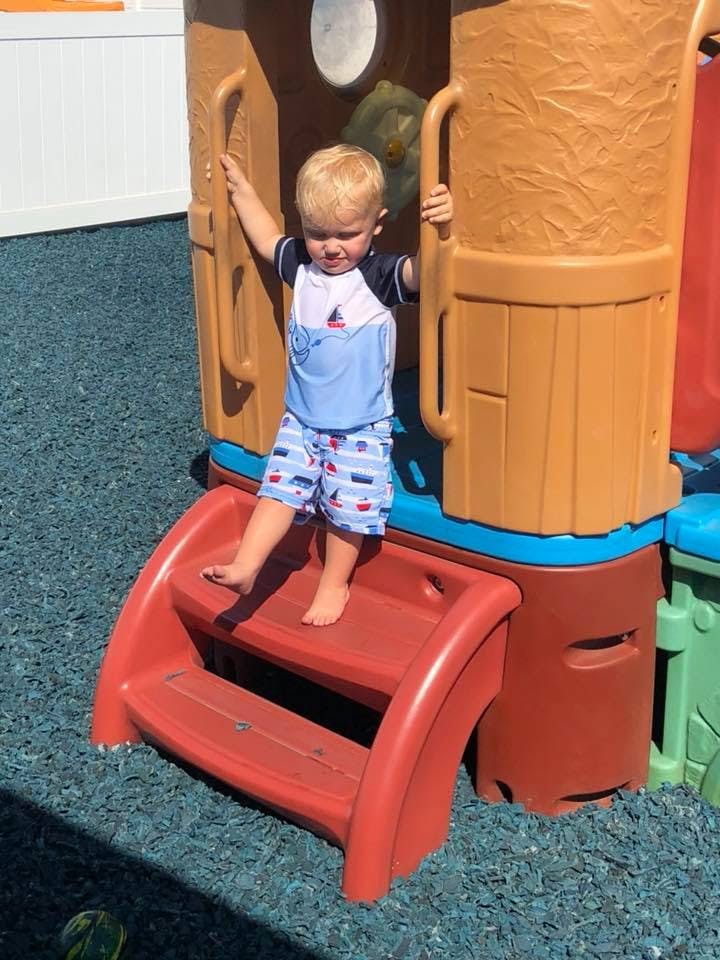 Child standing on steps of a playground structure