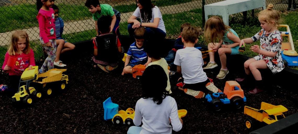 Children playing with toy trucks outdoors