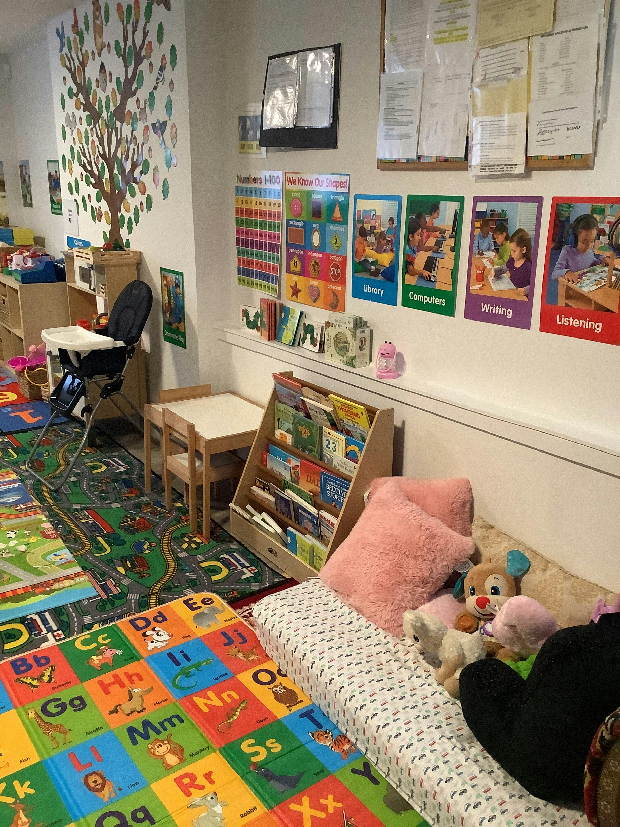 Children's play area with alphabet mat, road rug, high chair, and bookshelf