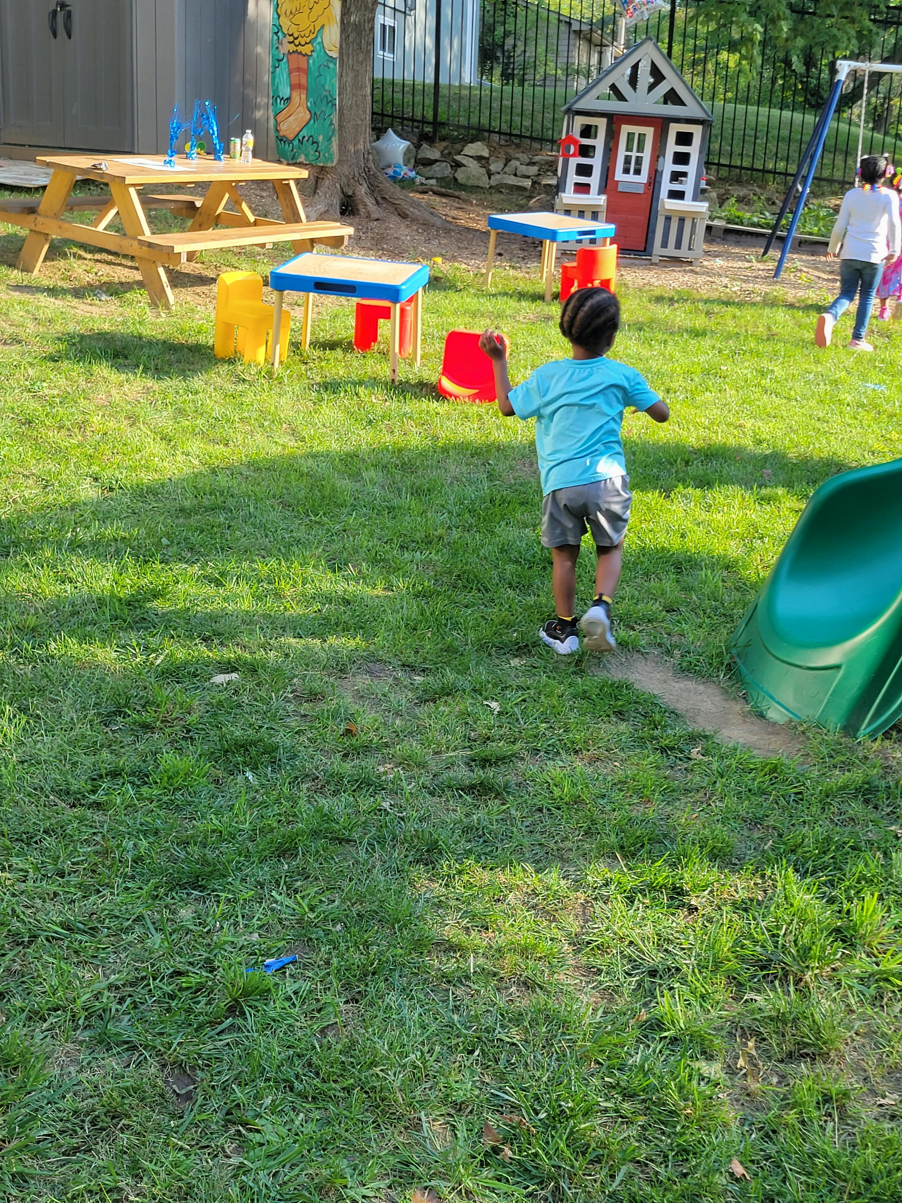 Child running on grass in a backyard playground