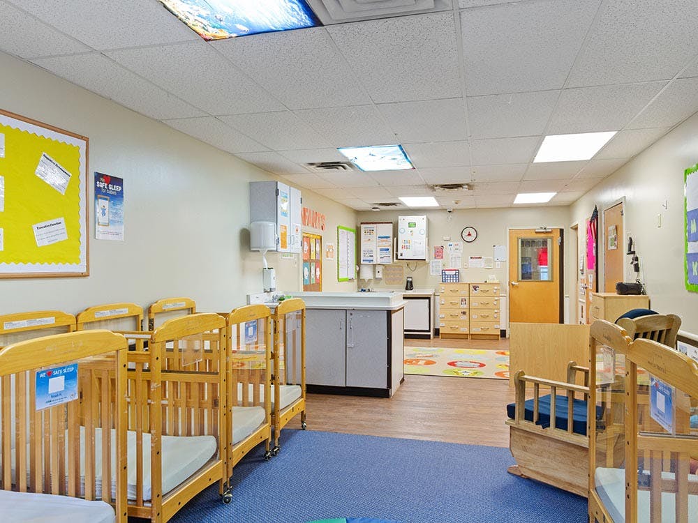 An empty nursery room with multiple cribs and a changing station