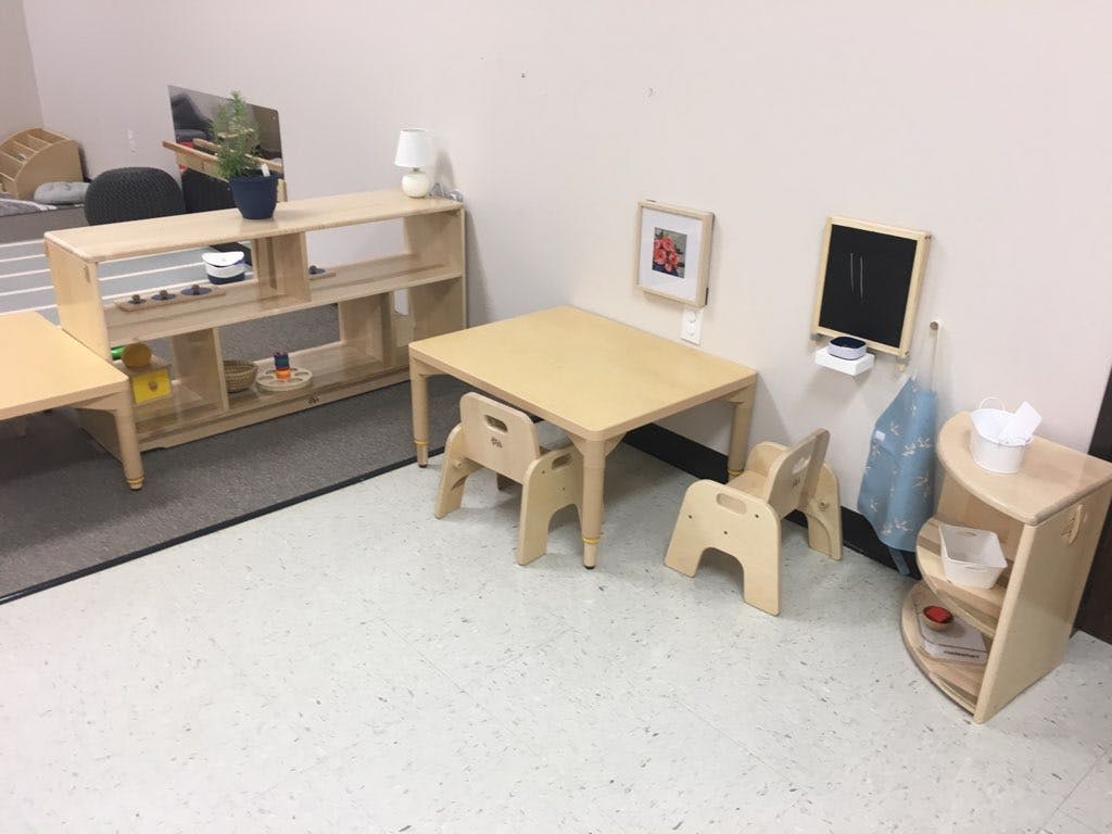 Classroom with small wooden tables, chairs, and shelves
