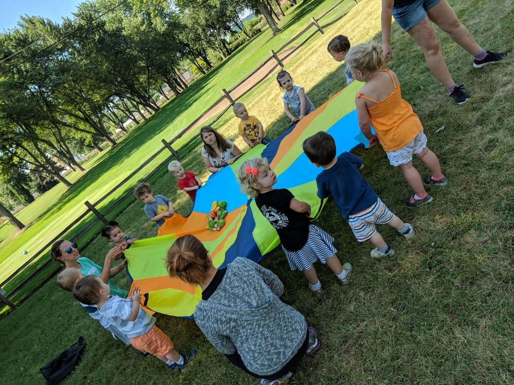 People and children playing with a colorful parachute outdoors