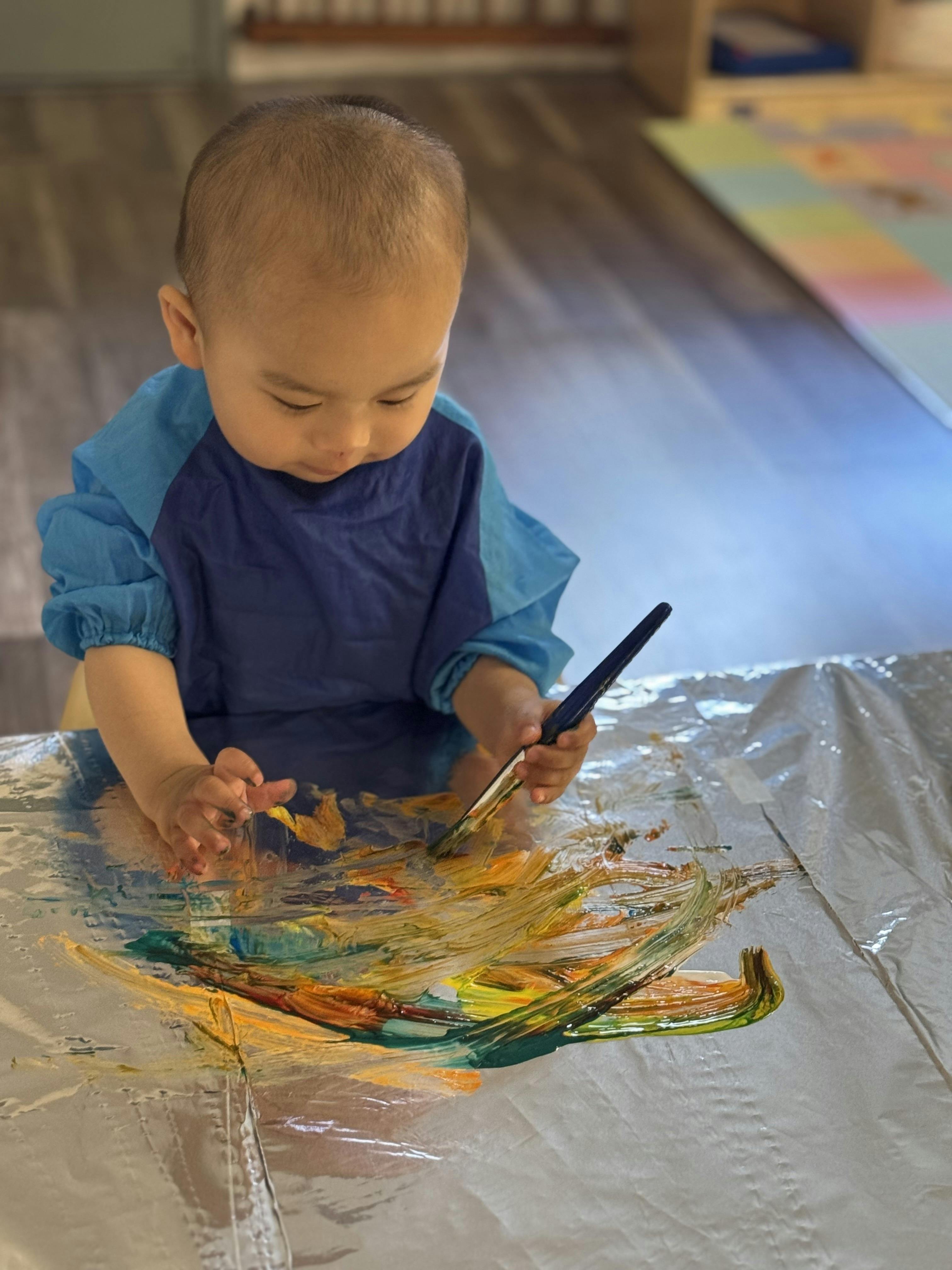 Child in a smock painting with a brush
