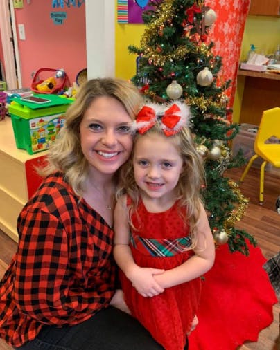 Adult and child posing in front of a Christmas tree