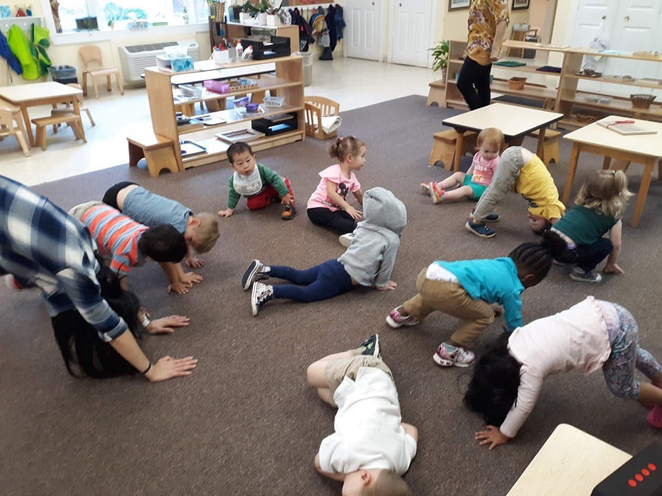 Adult and children doing exercises on the floor in a classroom