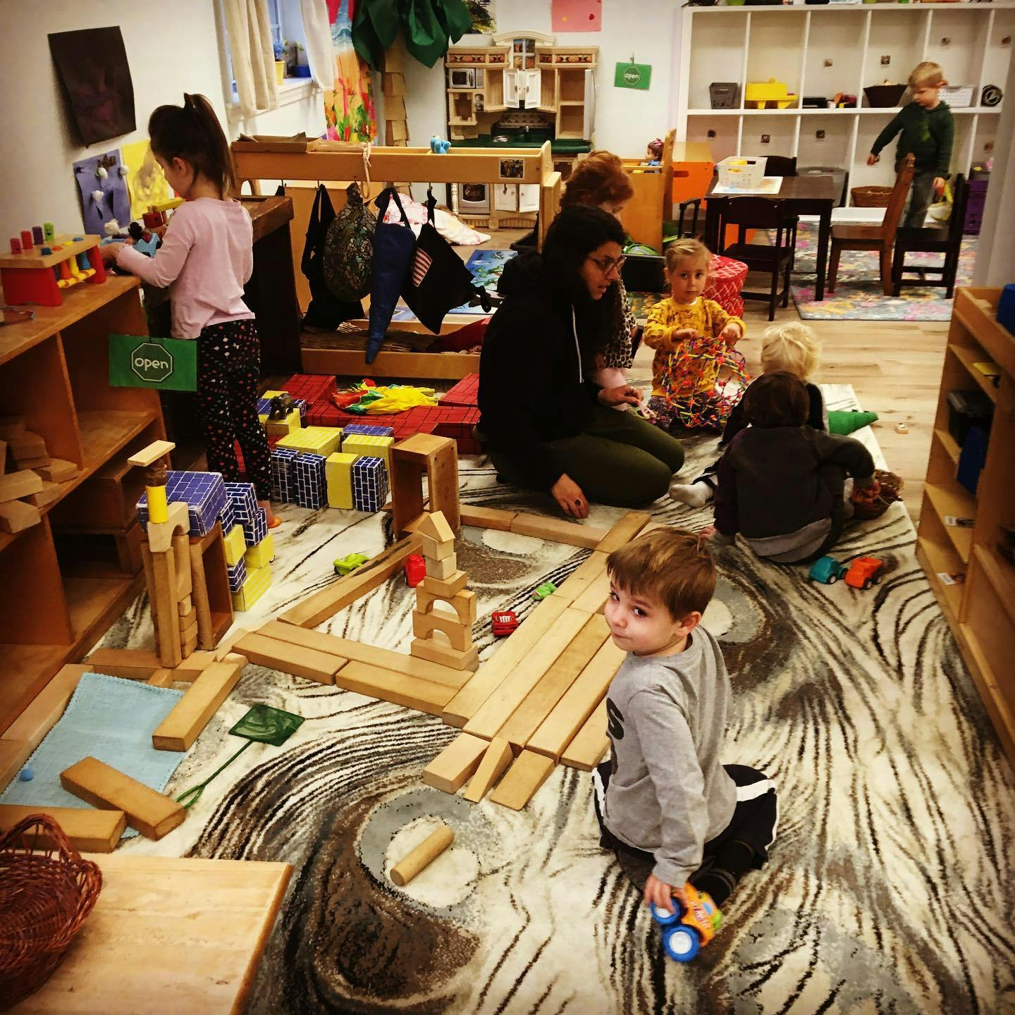 Adult and children playing with blocks and toys in a classroom