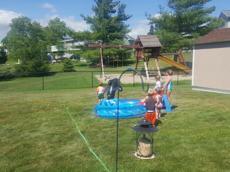 Children playing in a small inflatable pool in a grassy yard