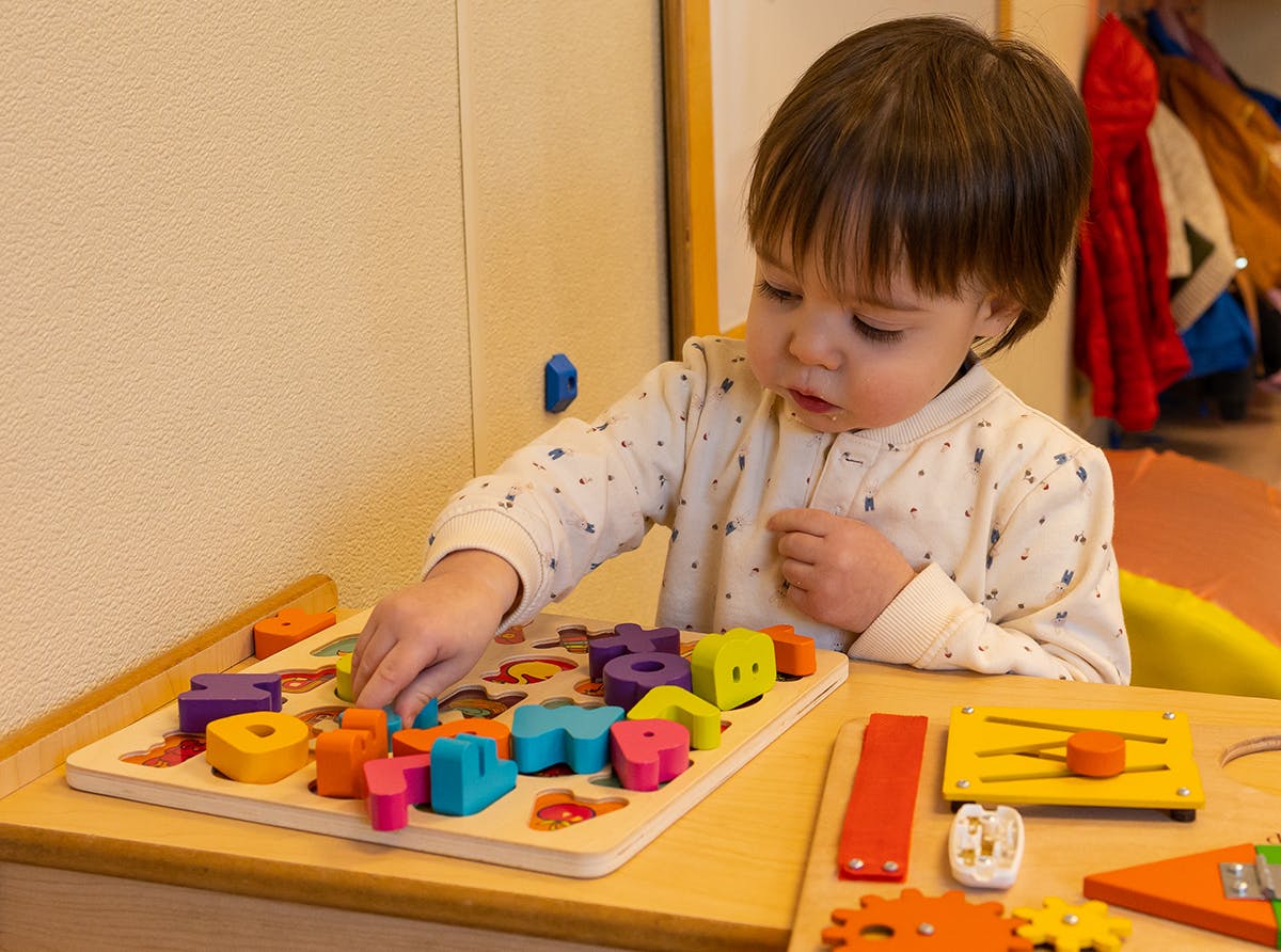 Child playing with a colorful wooden shape puzzle